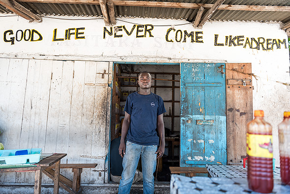 The salesman proudly posed in front of his motto of life